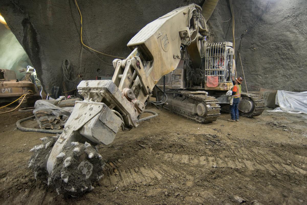 Large roadheader excavator positioned at entrance to underground platform cavern during tunnel construction work.