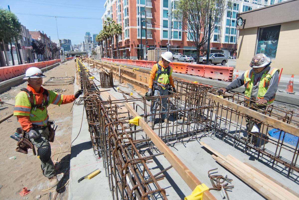 Construction workers install rebar and concrete forms for Central Subway surface platform at 4th and Broadway.