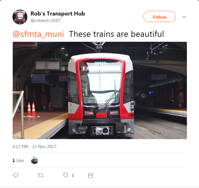 Red and white light rail train at station platform with overhead wires visible.