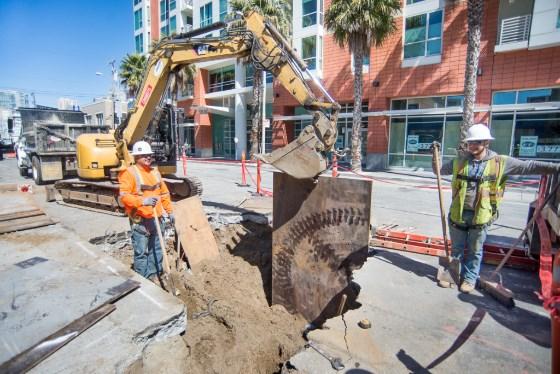 Construction crew excavates trench on 4th Street for Central Subway project using heavy equipment.