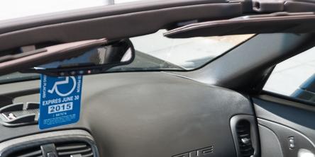 Handicapped placard hanging from rearview mirror inside vehicle