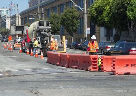 Construction workers and equipment on Brannan Street performing utility relocation work for Central Subway project.