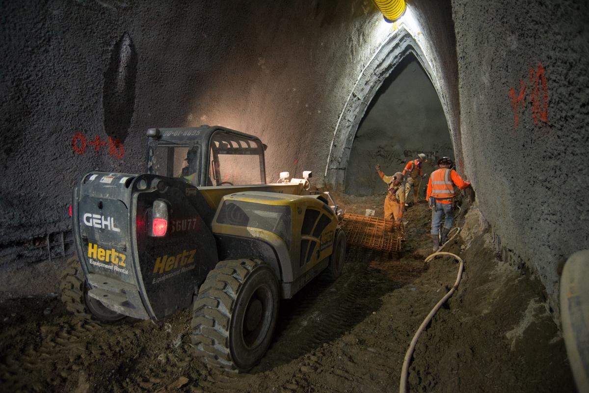 Construction crew operates heavy equipment inside underground tunnel during Chinatown Station excavation work.