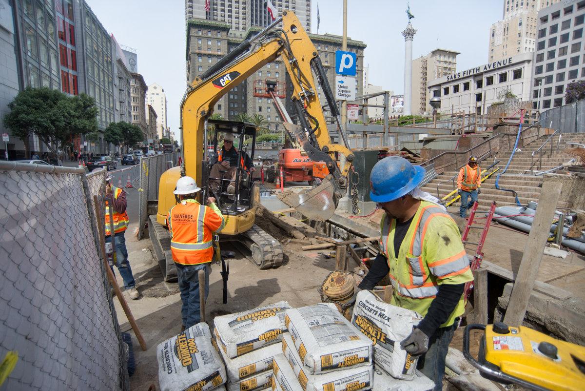 Construction workers unload concrete materials at underground transit station site on Geary at Stockton Street.