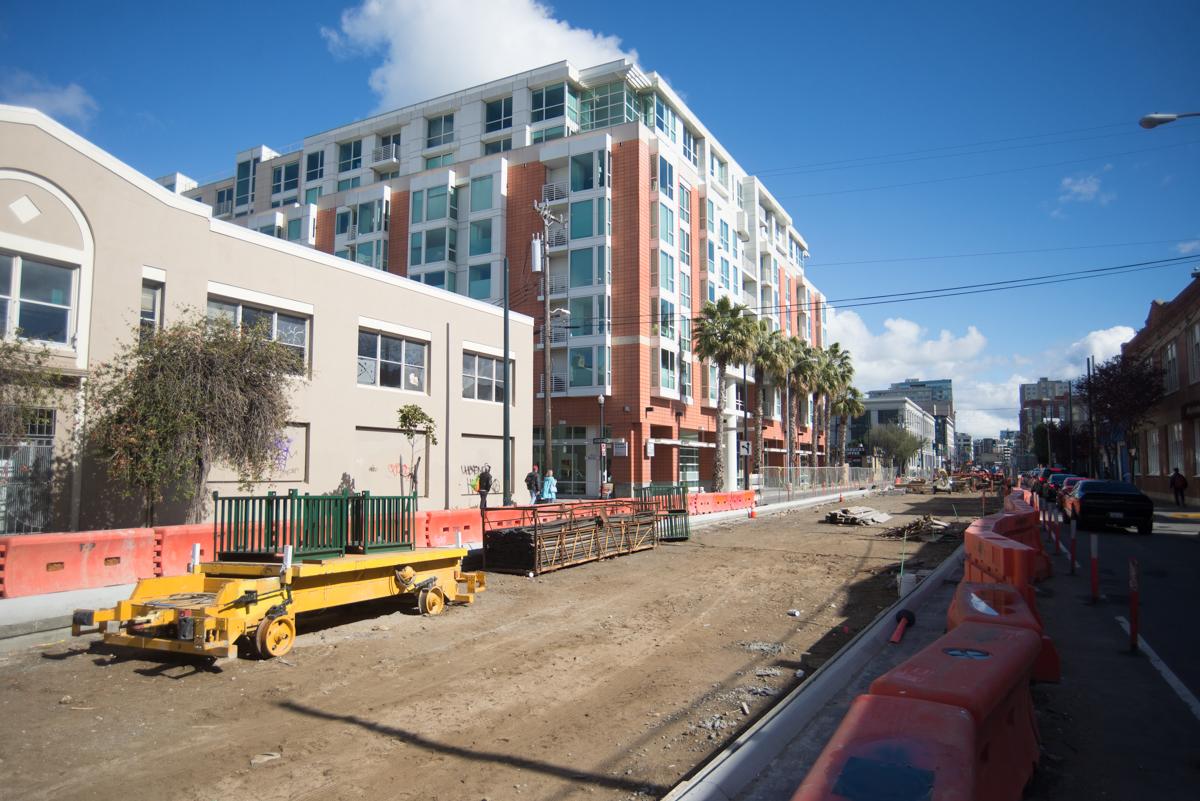 Construction site with equipment and barriers along street near new residential building
