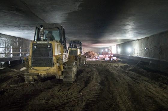 Bulldozers and excavation equipment inside an underground tunnel during construction work.