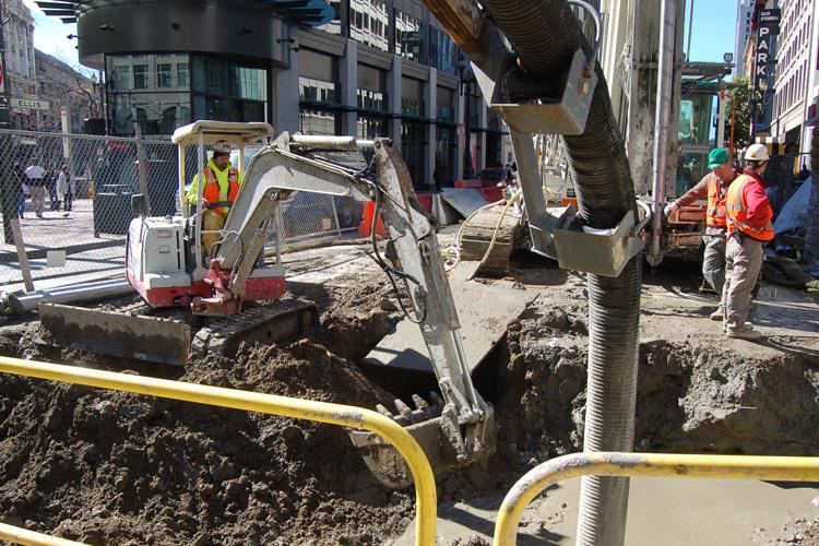 Construction crew operates excavator at Ellis Street jet grouting site for transit tunnel preparation work.