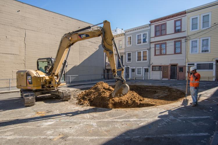 Excavator with operator removing soil from parking lot at Stockton Street for ground improvement work.