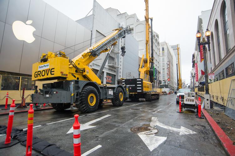 Yellow Grove mobile crane on Stockton Street with traffic cones and construction barriers near Apple Store.