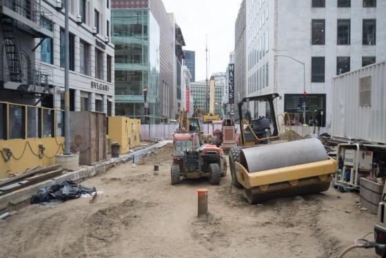 Construction equipment and machinery on Clementina Street with surrounding buildings and closed sidewalks.