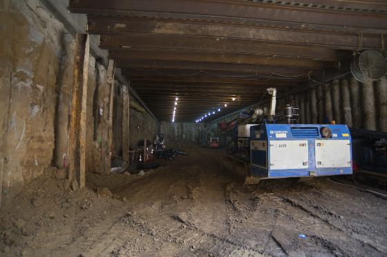 Underground excavation work on Stockton Street with blue equipment and exposed wooden support beams.