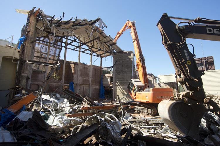 Demolition equipment dismantling the Pagoda Palace building facade with debris scattered on the ground.