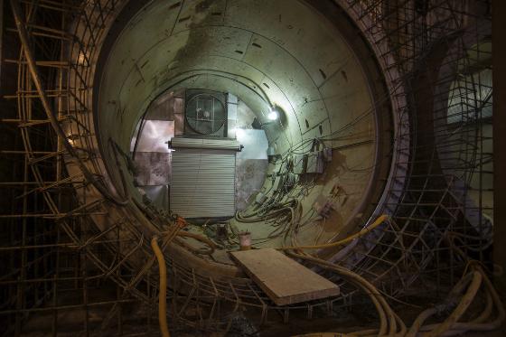 Interior view of subway tunnel under construction with metal framework and white entrance structure.