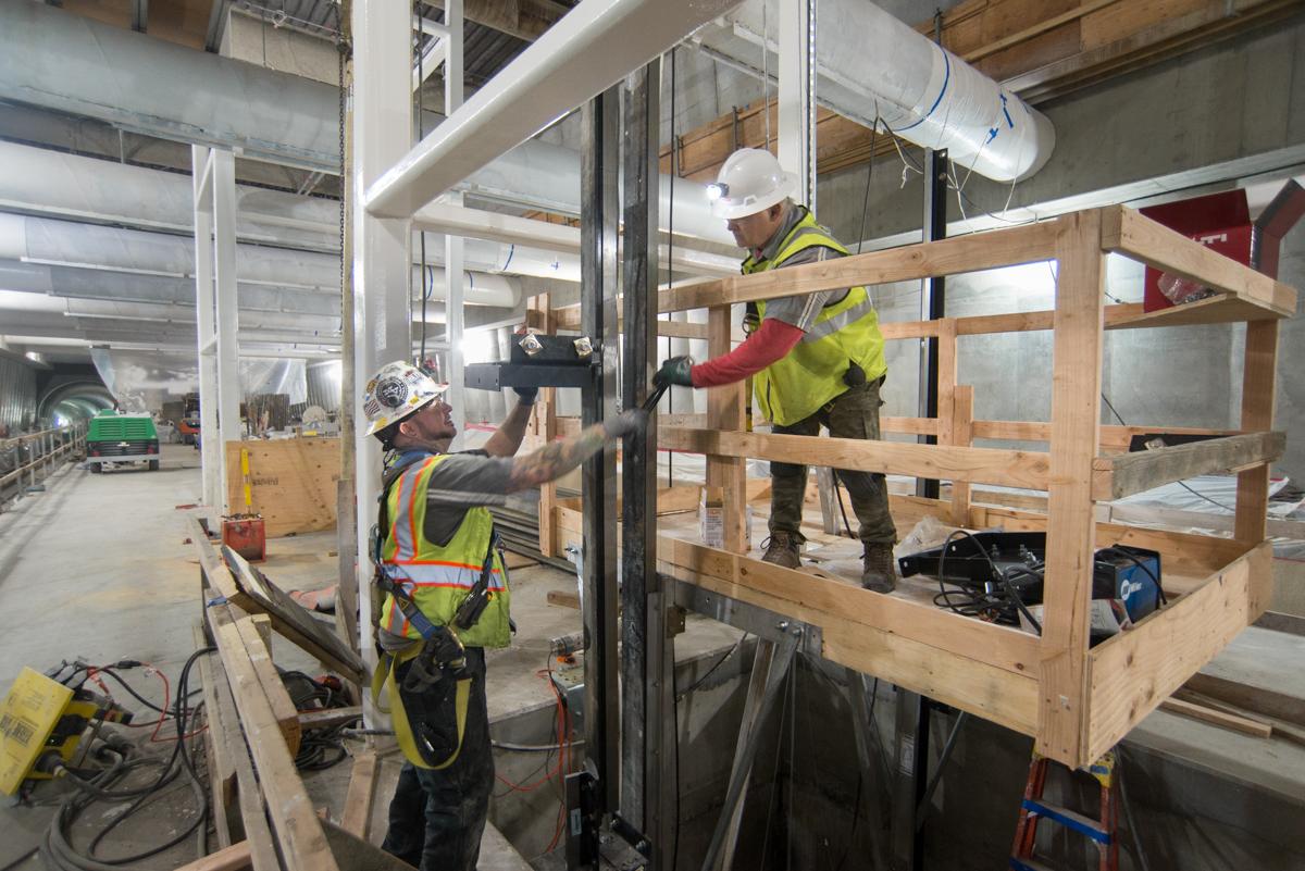 Two construction workers in safety gear install framing inside an industrial building under renovation.
