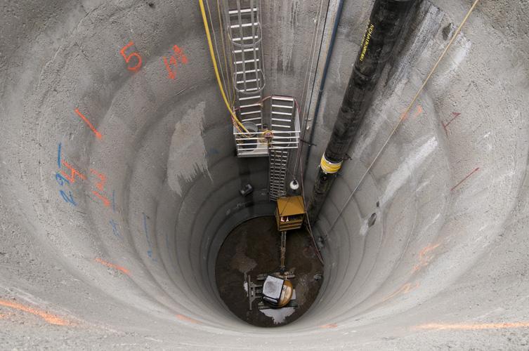 Overhead view of deep concrete shaft with equipment and pipes for Central Subway tunnel construction on Ellis Street.