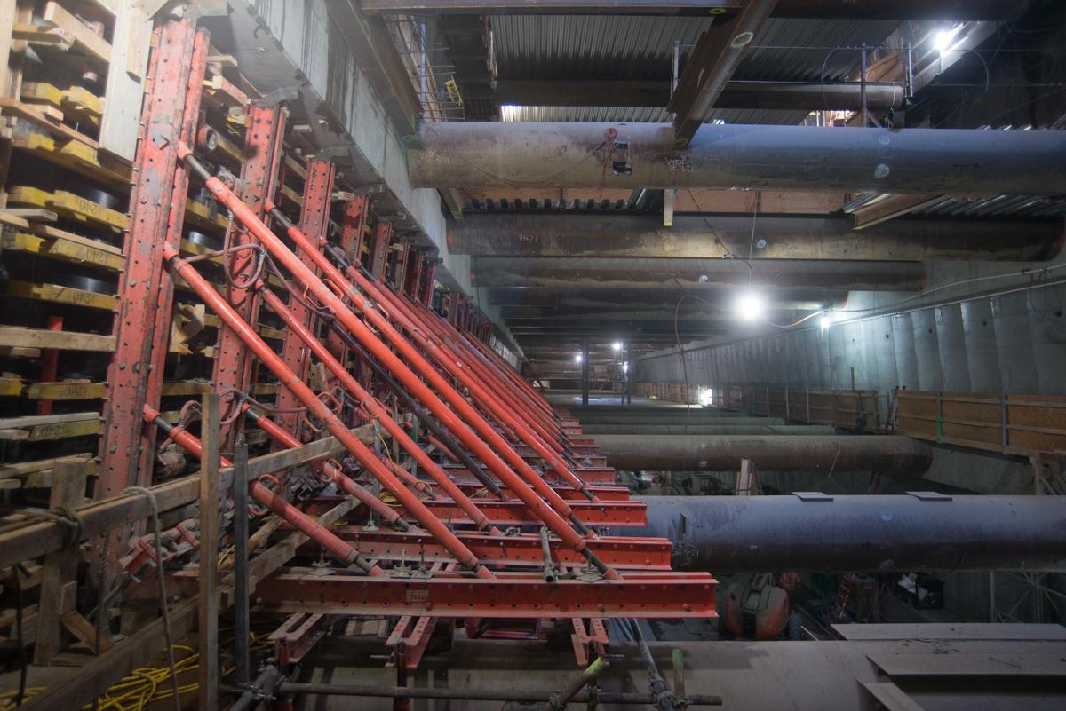 Red structural bracing and concrete forms installed in underground transit station construction area.