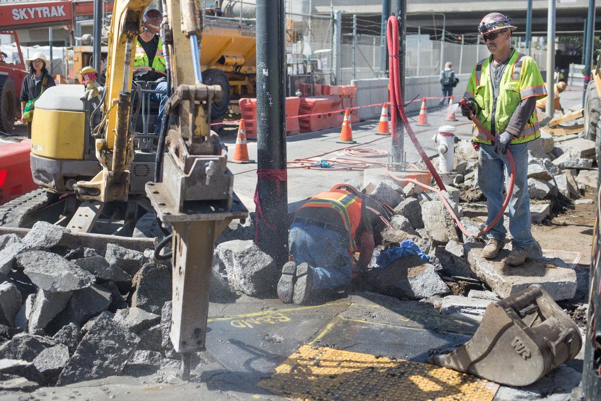 Construction workers break up concrete with an excavator at 4th and Bryant street intersection during sidewalk and roadway restoration.