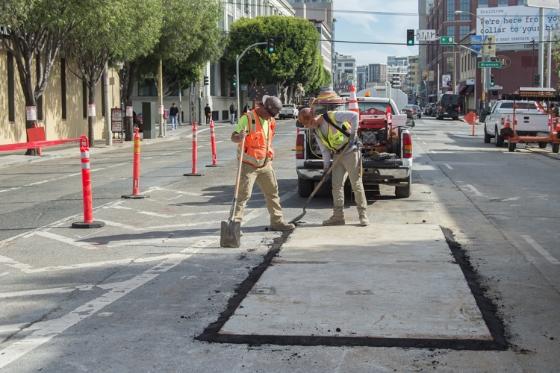 Construction workers cover unfinished subway work on 4th Street with temporary plating.