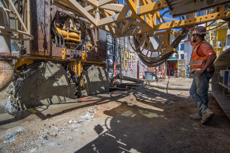 Worker inspects hydromill excavation equipment at Chinatown Station construction site.