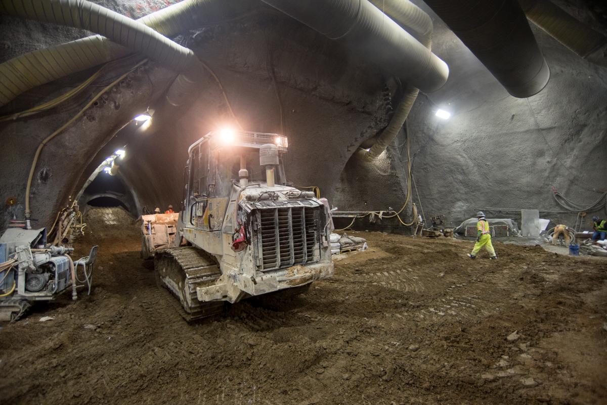 Underground tunnel construction site with excavator and work crew beneath Washington and Stockton intersection.