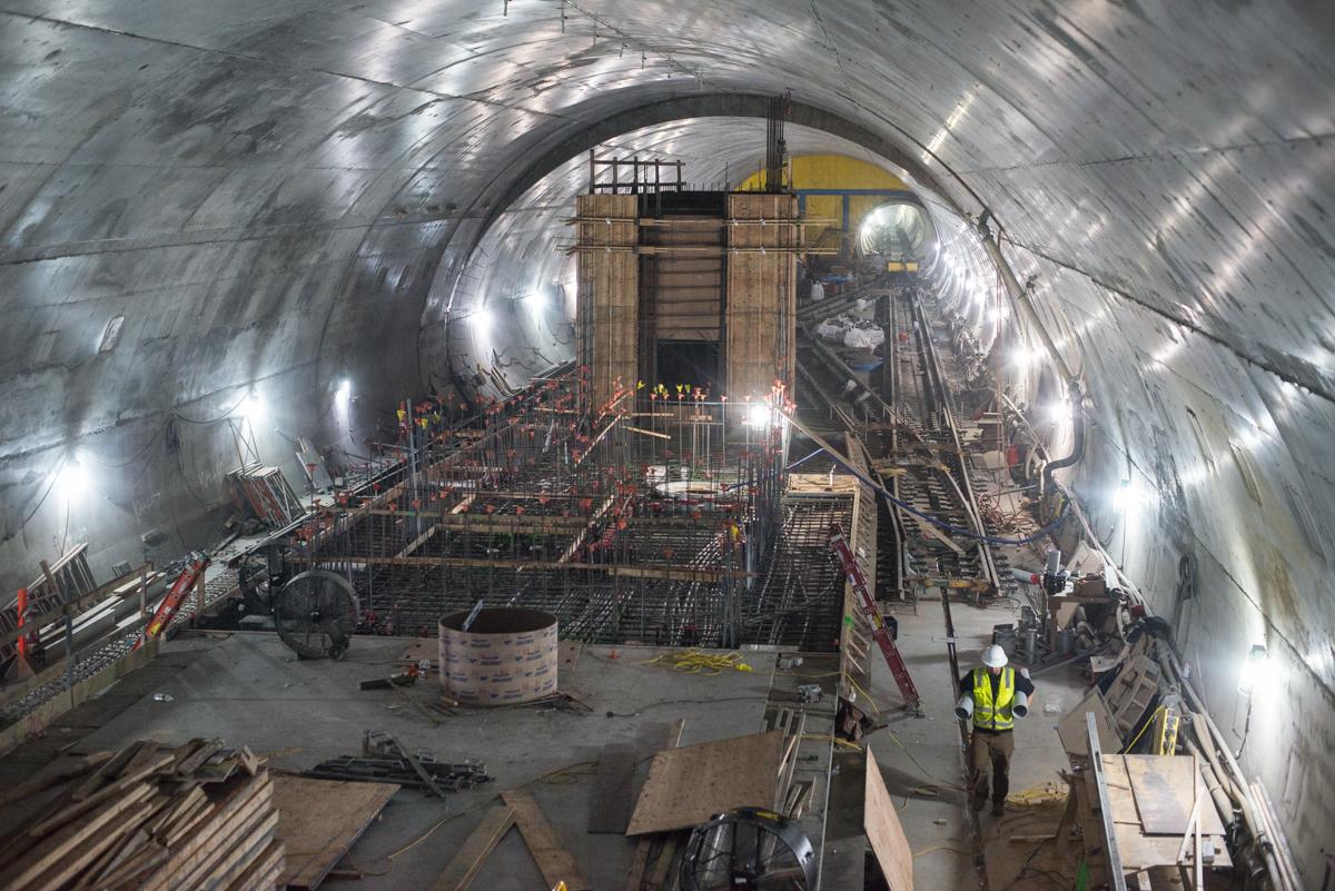 Construction inside Chinatown Station tunnel showing concrete platform structure, formwork, and lighting during Central Subway project.