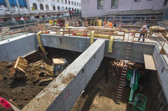 Excavation pit with concrete walls and construction equipment at future Chinatown Station site.