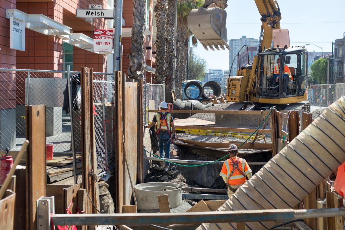 Construction crew installing water line and catch basin at 4th and Welsh Street with excavator and heavy equipment.