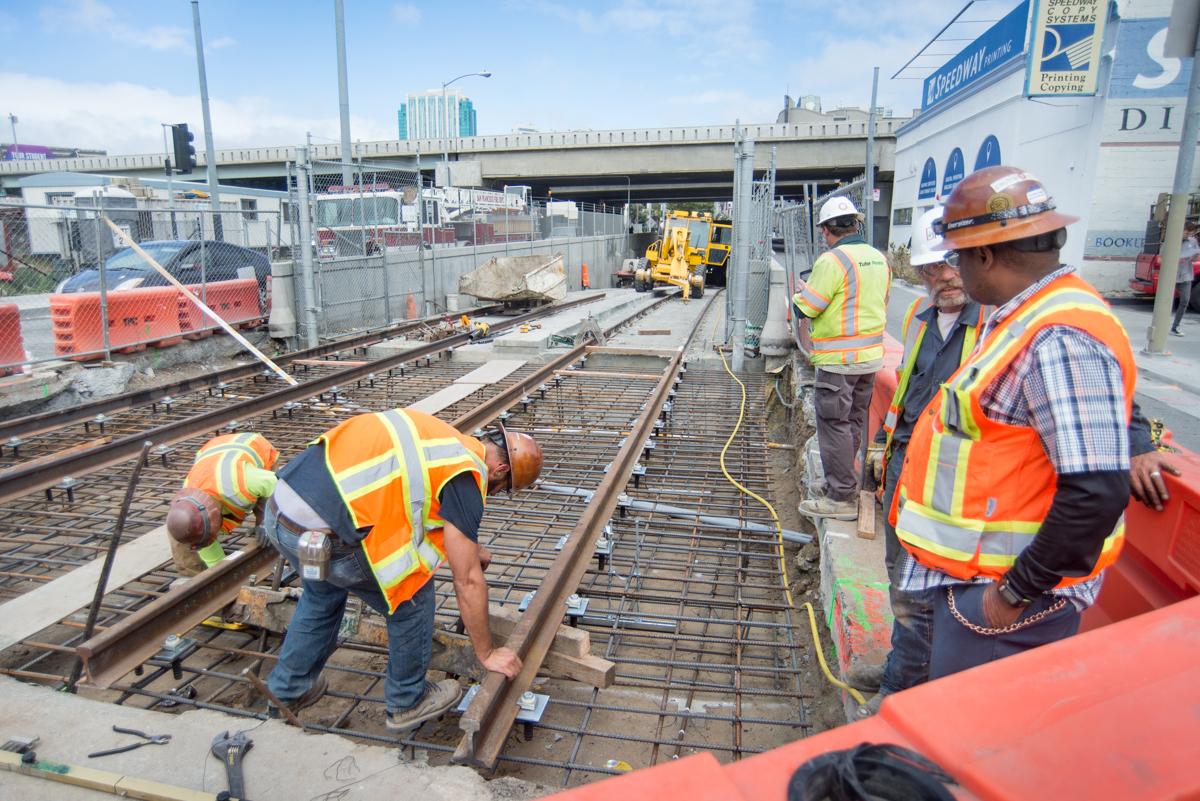 Construction workers install surface tracks at 4th and Bryant tunnel portal.