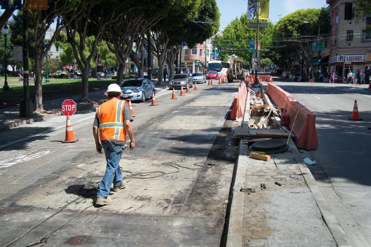 Worker in safety vest and hard hat directing traffic on Washington Street during fire hydrant construction work.