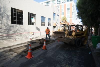 Construction crew performing pothole utility work on Welsh Alley with heavy equipment and traffic cones.