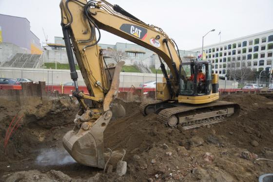 CAT excavator removes pavement chunks at construction site for future Yerba Buena/Moscone Station.