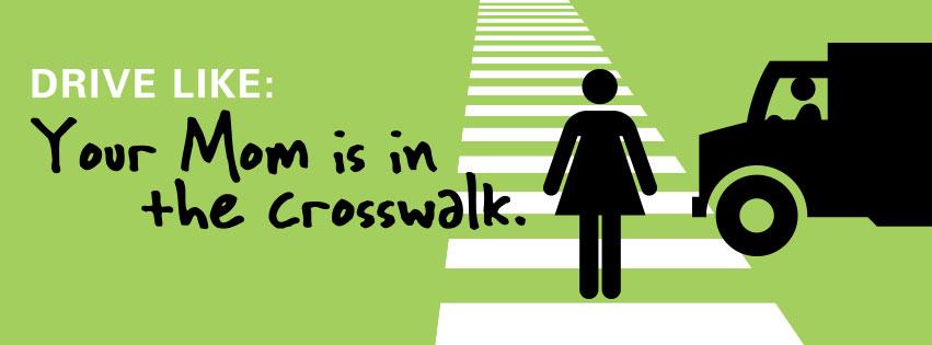 Truck stopped at crosswalk with pedestrian crossing, text reads "Drive like: Your Mom is in the crosswalk"