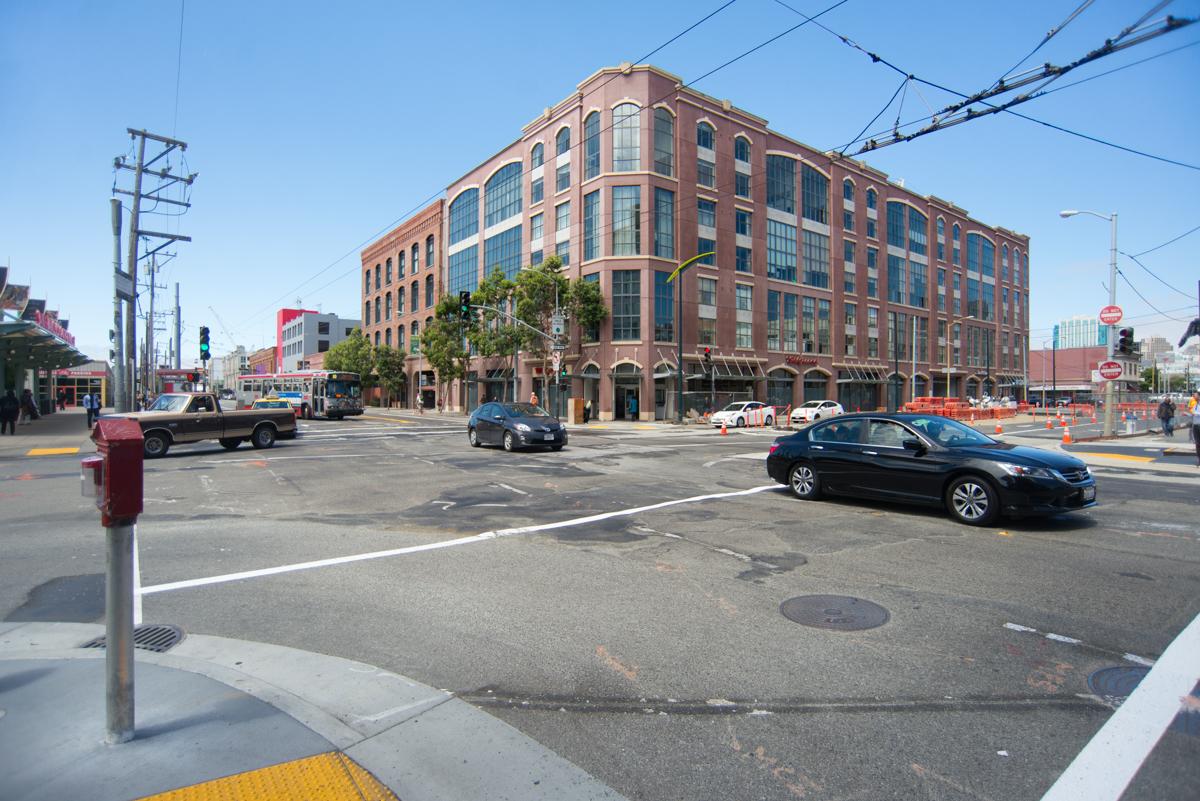 Intersection of 4th Street and Townsend with historic brick building, traffic, and construction barriers.