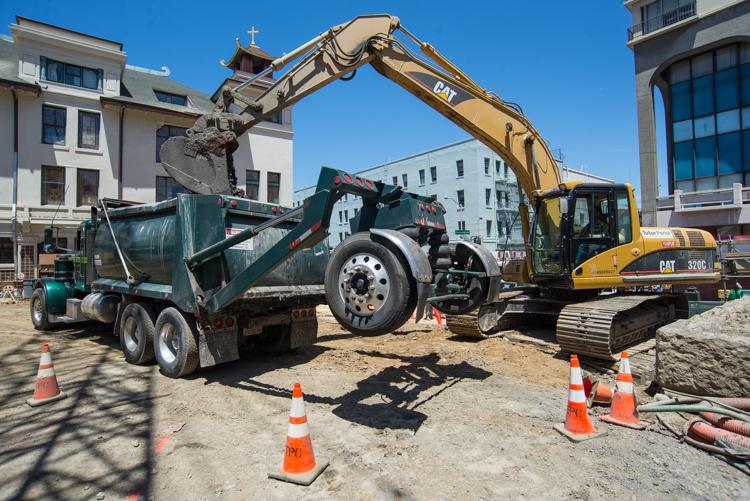Excavator loading debris into dump truck at Chinatown Station construction site