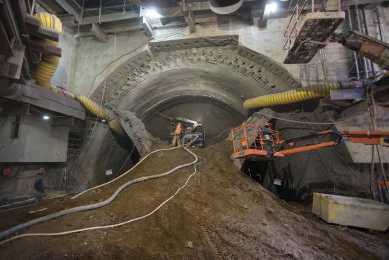Workers excavate soil inside a large concrete tunnel under construction for the Chinatown Station.