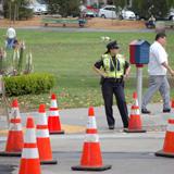 Traffic control personnel direct work on street with orange cones and equipment visible in background.