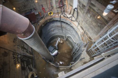 # Alt Text</p>
<p>Overhead view of circular underground shaft with rebar installation and construction equipment for Chinatown station emergency exit.