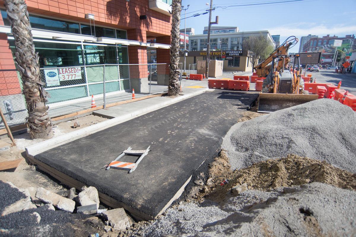Construction site on 4th Street with utility trench, equipment, and materials staged along sidewalk.