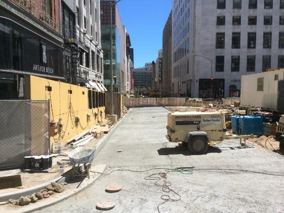 Construction site on Stockton Street with equipment, barriers, and urban buildings.