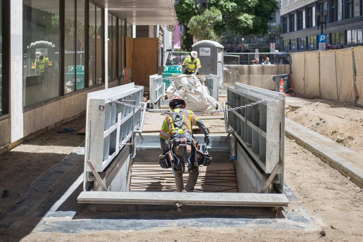 Worker on motorcycle descending ramp into underground construction site at Stockton and O'Farrell.