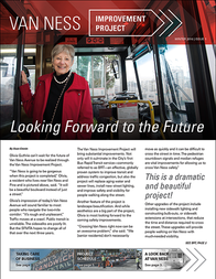 Bus operator in red uniform standing inside Van Ness bus with improvement project newsletter cover displayed