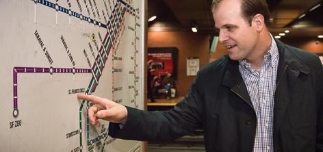 Man pointing at tactile transit map with raised characters and Braille