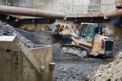 Bulldozer excavating beneath concrete structure during underground construction work.