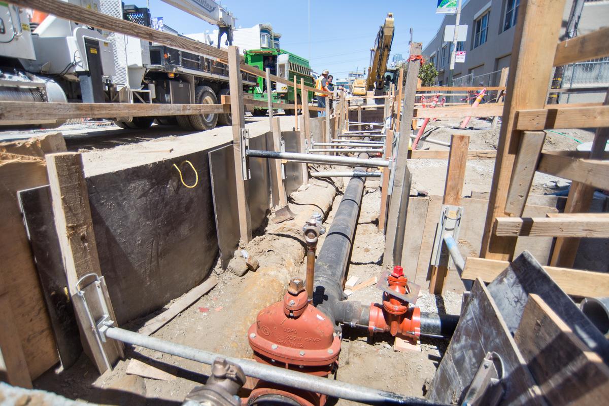 Construction trench with newly installed water lines and valves on 4th Street.