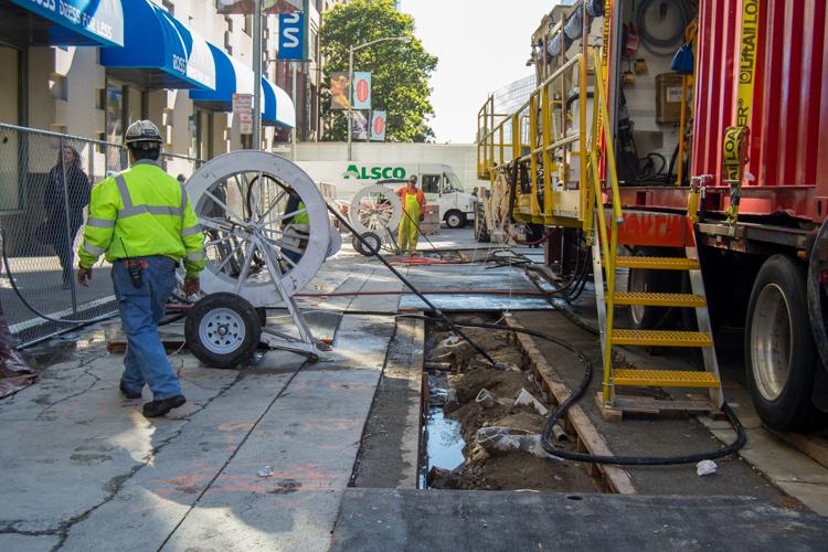 Construction crew operates concrete pump truck on 4th Street during underground tunnel boring work beneath Market Street.
