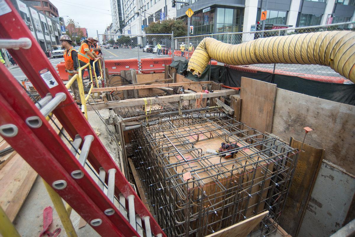 Construction pit with steel rebar framework and concrete forms for new sewer manhole installation on 4th Street.