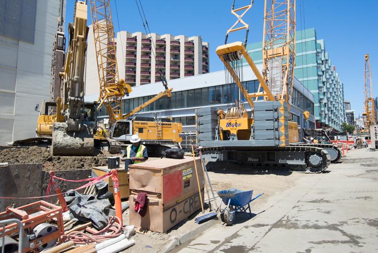 Construction cranes and heavy equipment at Yerba Buena/Moscone Station excavation site with surrounding buildings