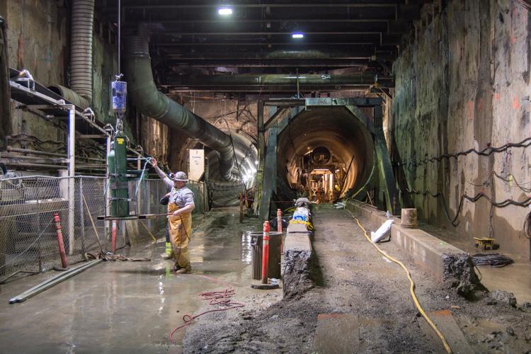 Workers in hard hats inside large underground tunnel during Central Subway construction in San Francisco.