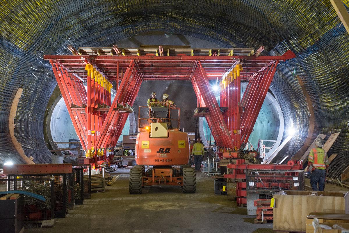 Construction workers operate heavy machinery inside a tunnel under construction for the Central Subway project.