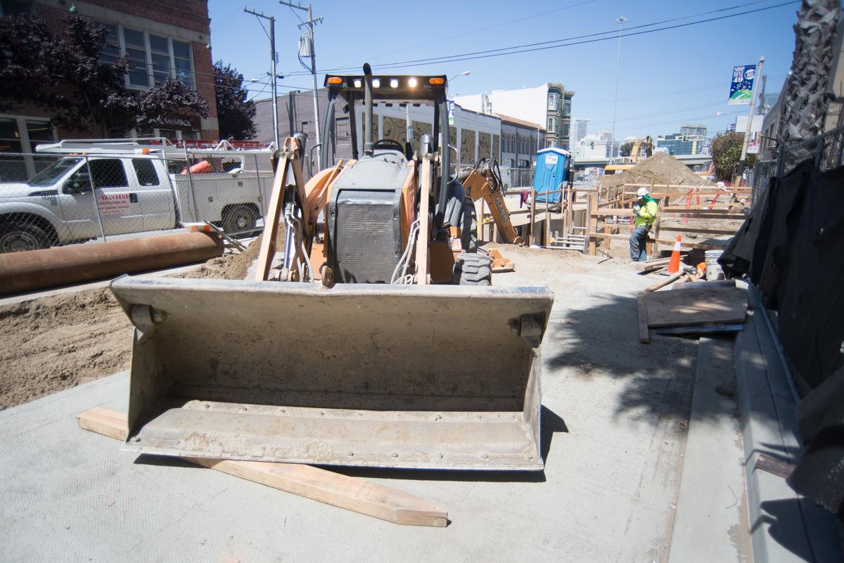 Construction equipment and workers at tunnel construction site with concrete pump hose disassembly in progress.